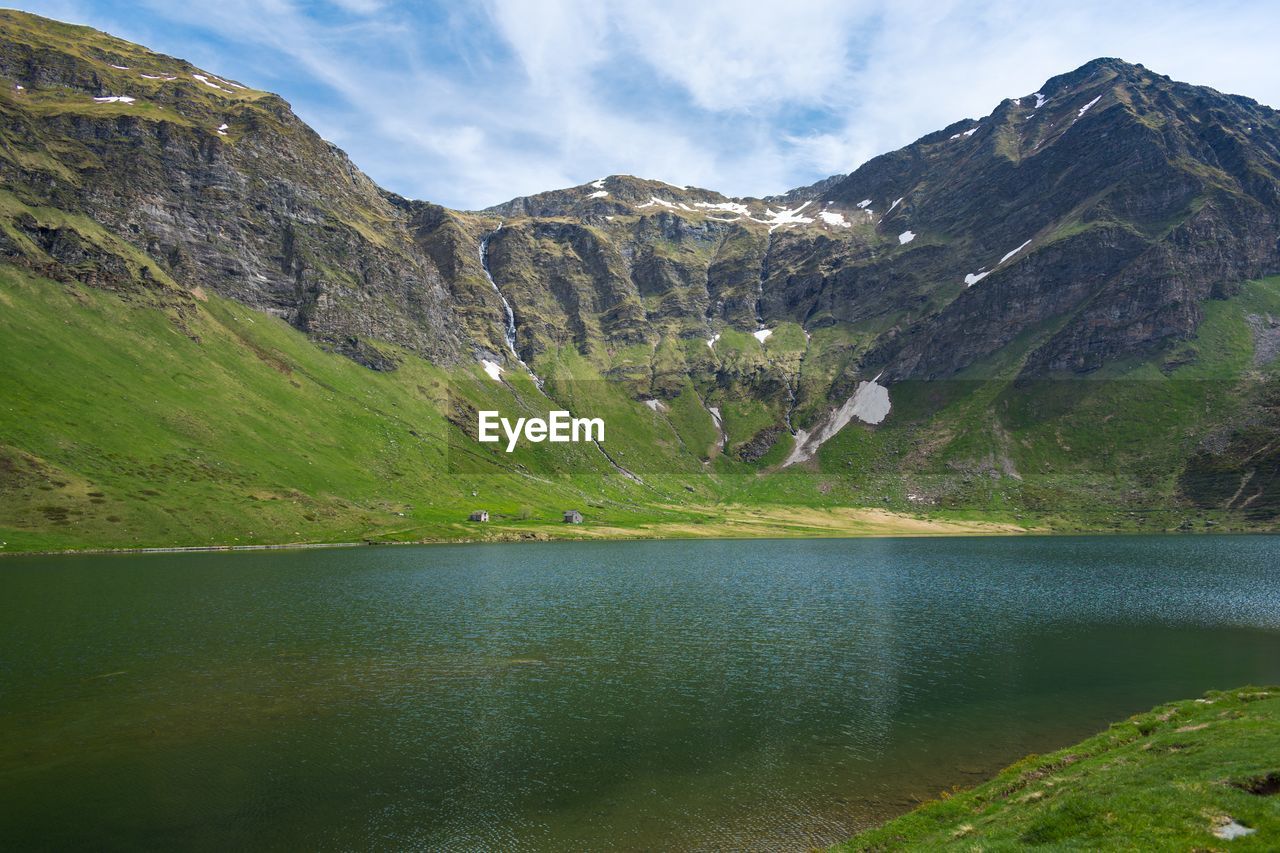 Scenic view of lake by mountains against sky