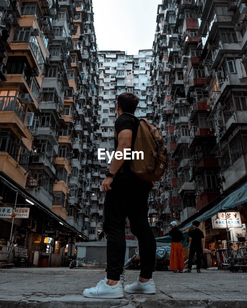 Full length of man standing against buildings on walkway in city