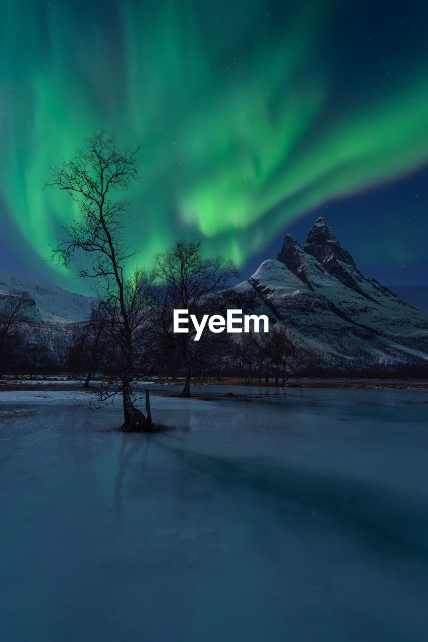 A beautiful show of northern lights above the imposing peaks of otertinden with moonlight.