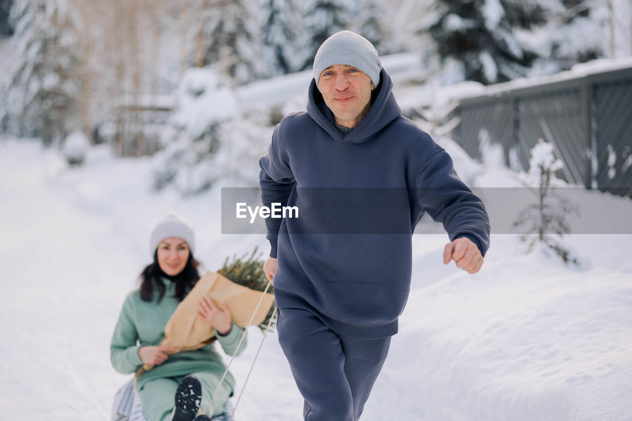 Smiling man giving sledding ride to woman. love and leisure concept.