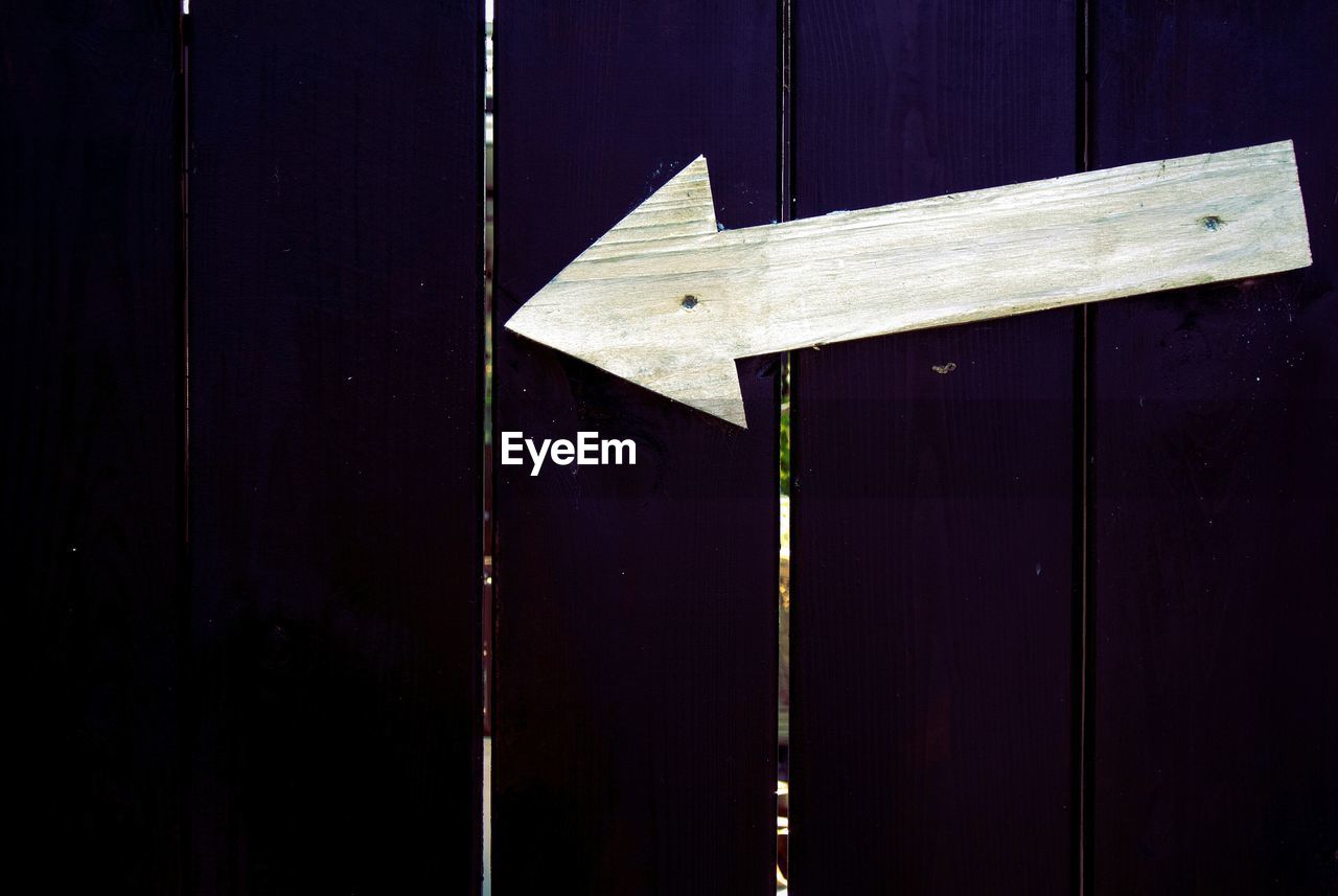 White arrow symbol on purple wooden fence