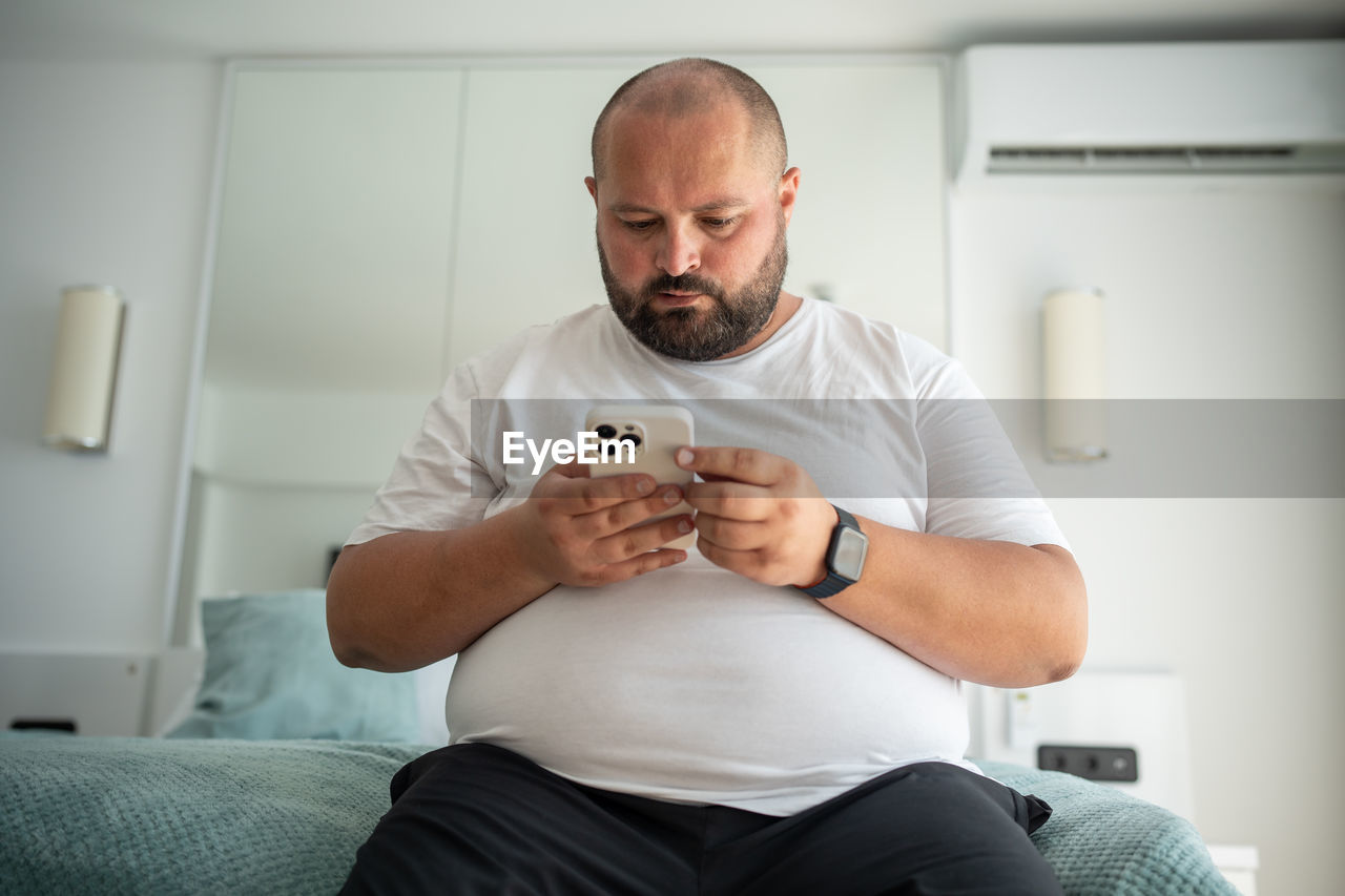portrait of senior man using mobile phone while sitting on sofa at home