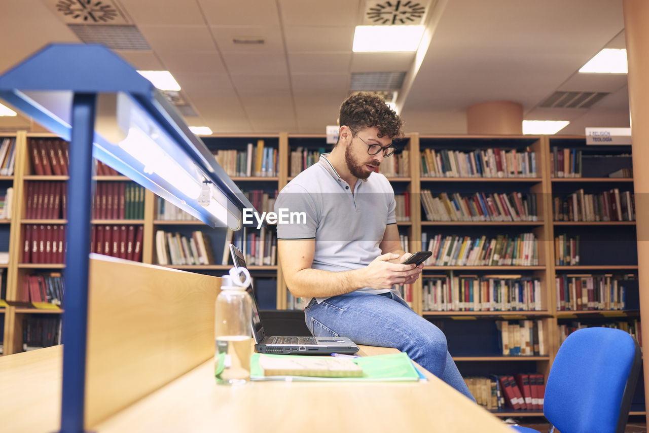 Portrait of a brown boy using a mobile phone in a library