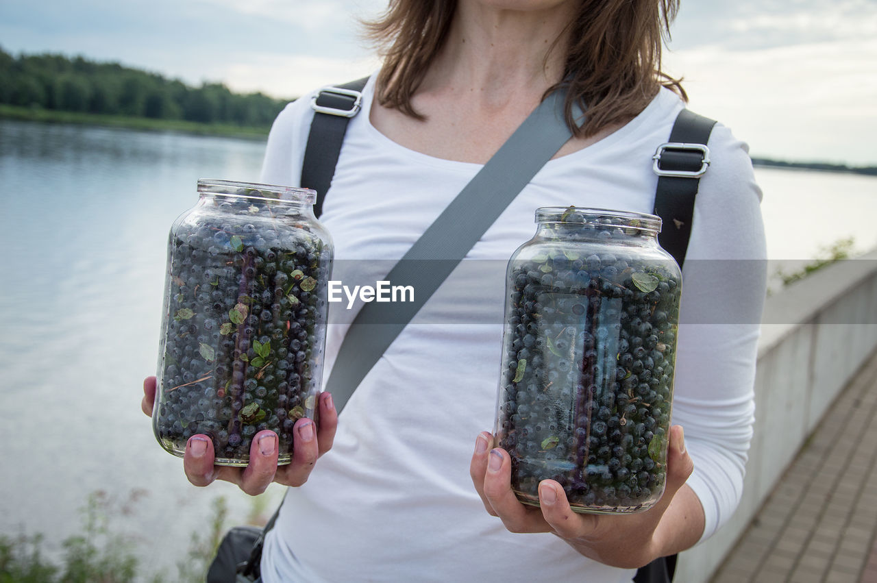 Midsection of woman holding glass jar