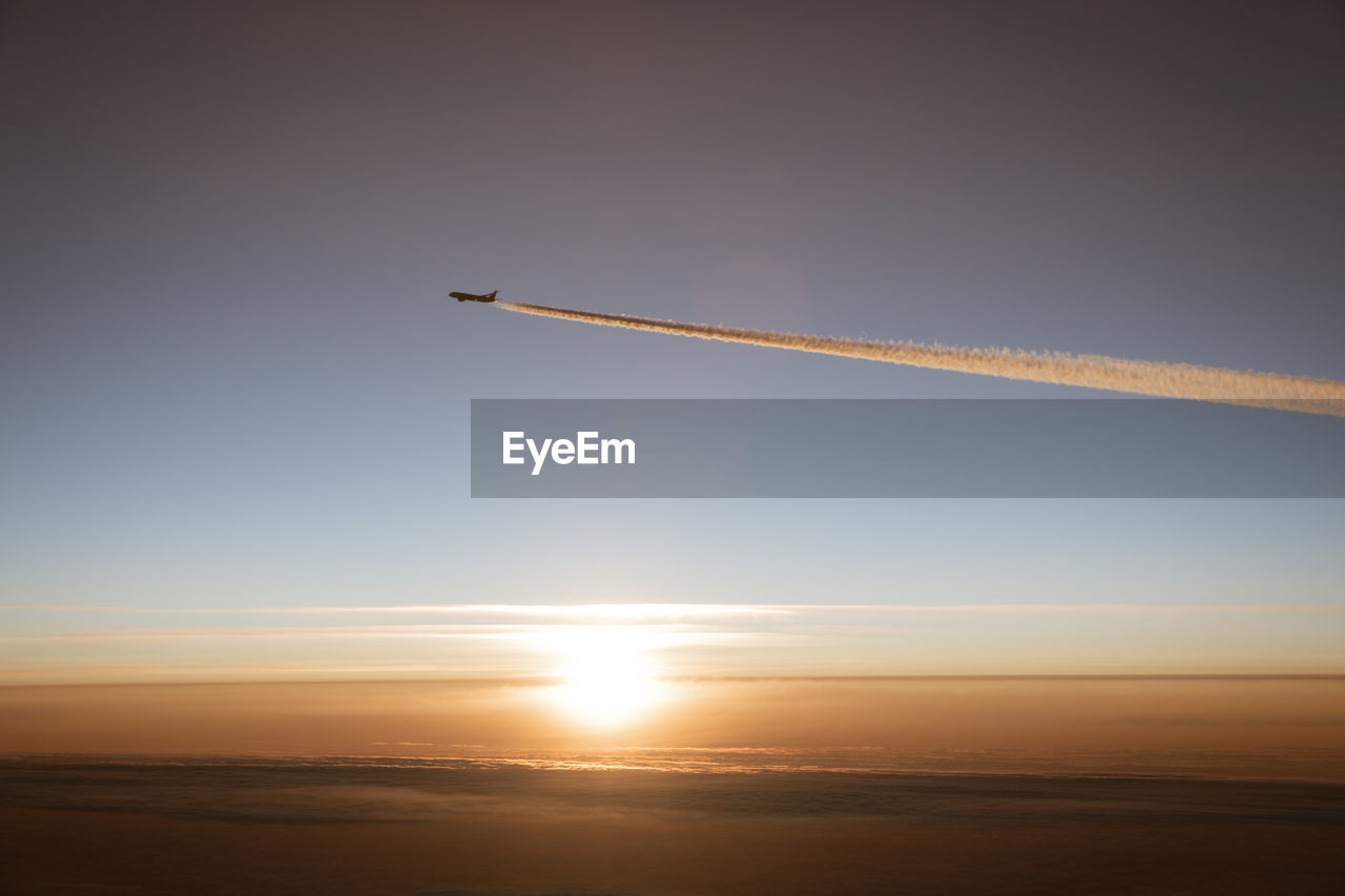 low angle view of airplane flying over sea against sky during sunset