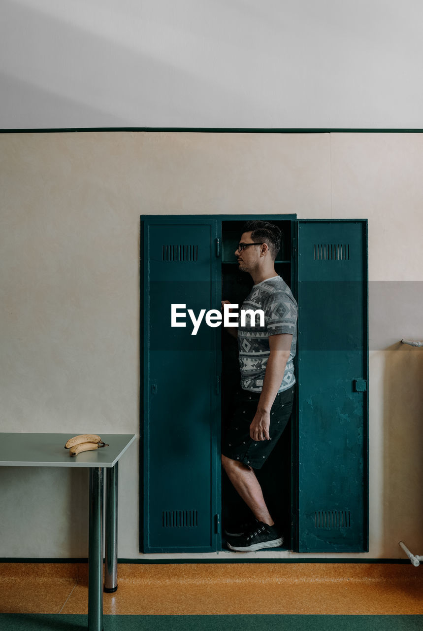 Man standing in cupboard at home