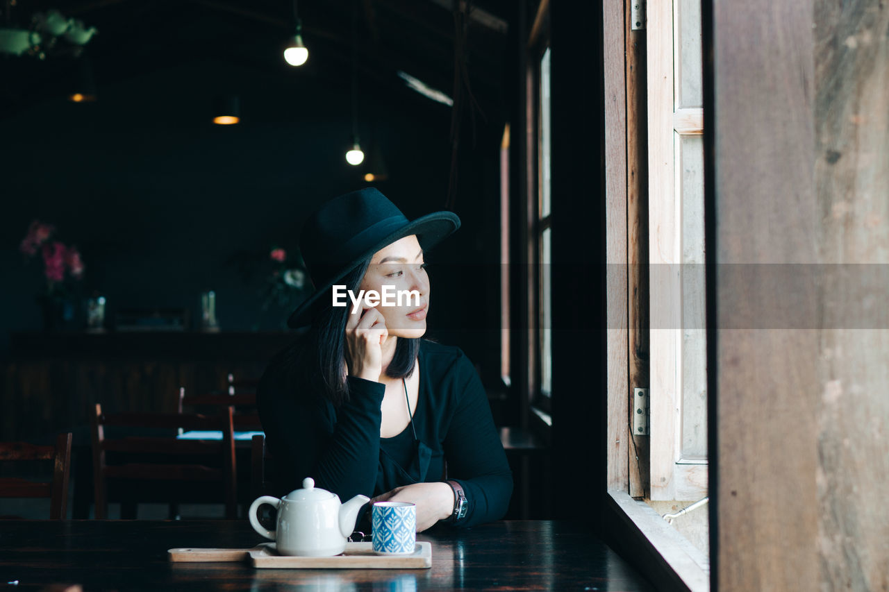 Young woman sitting on table at restaurant