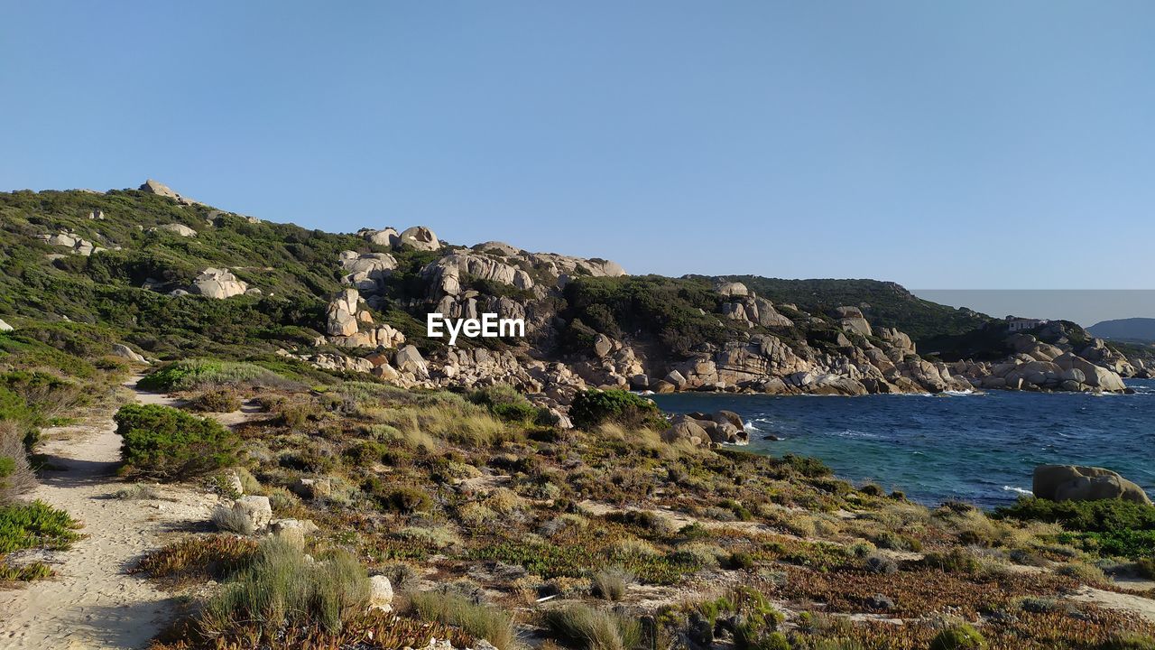 Scenic view of sea and mountains against clear blue sky