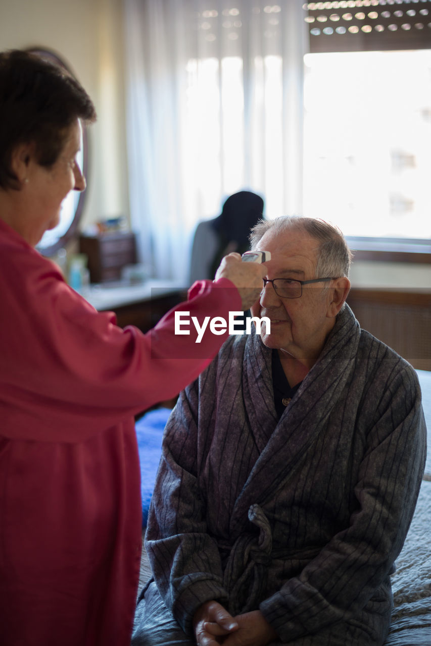 Woman checking temperature of patient