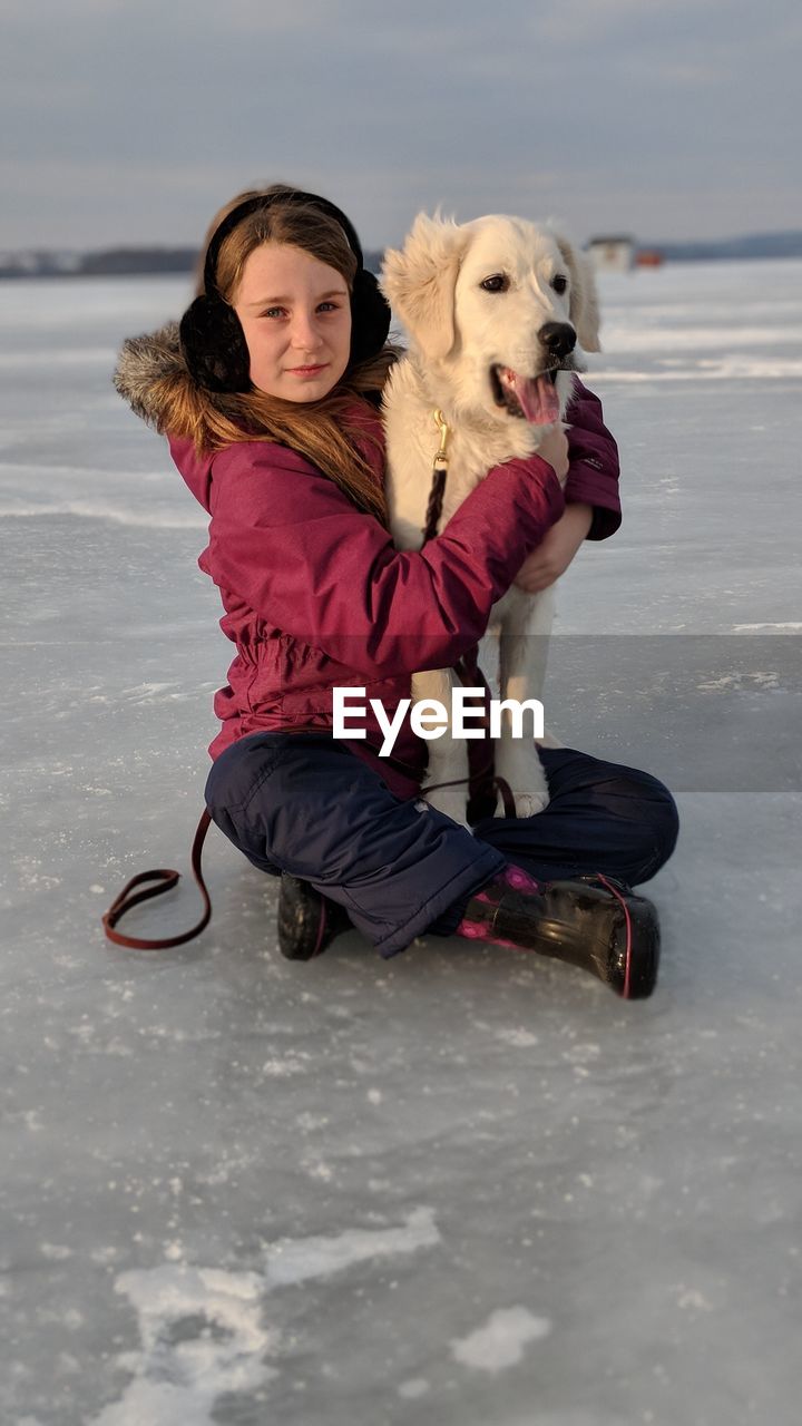 Portrait of girl with dog on frozen lake
