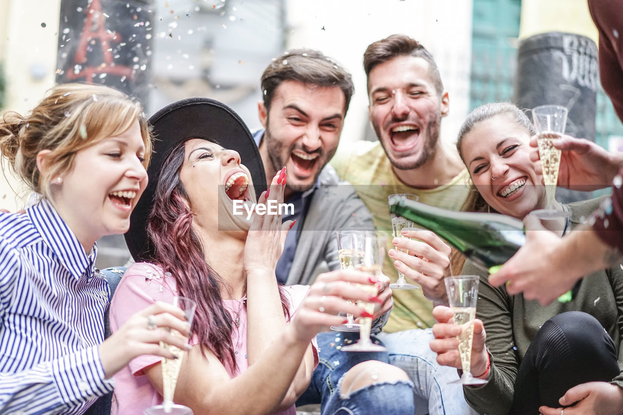 Cheerful male and female friends enjoying champagne during party outdoors