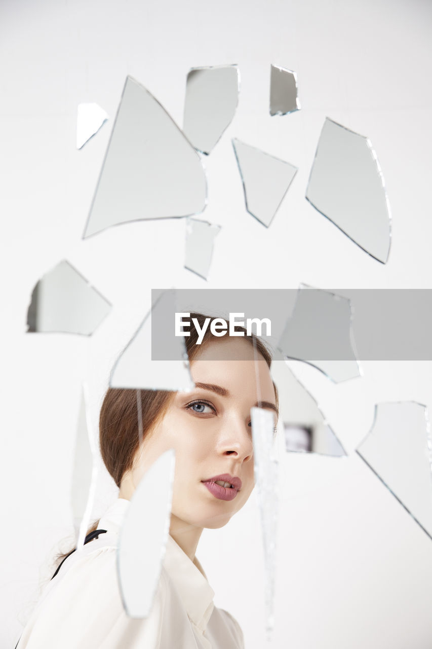 Young woman behind broken mirror