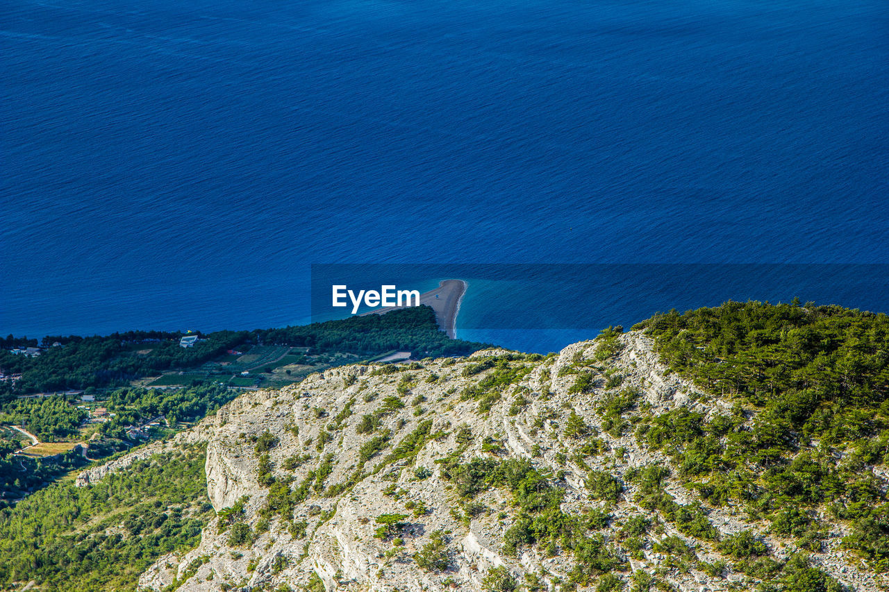 High angle view of sea and mountains against blue sky