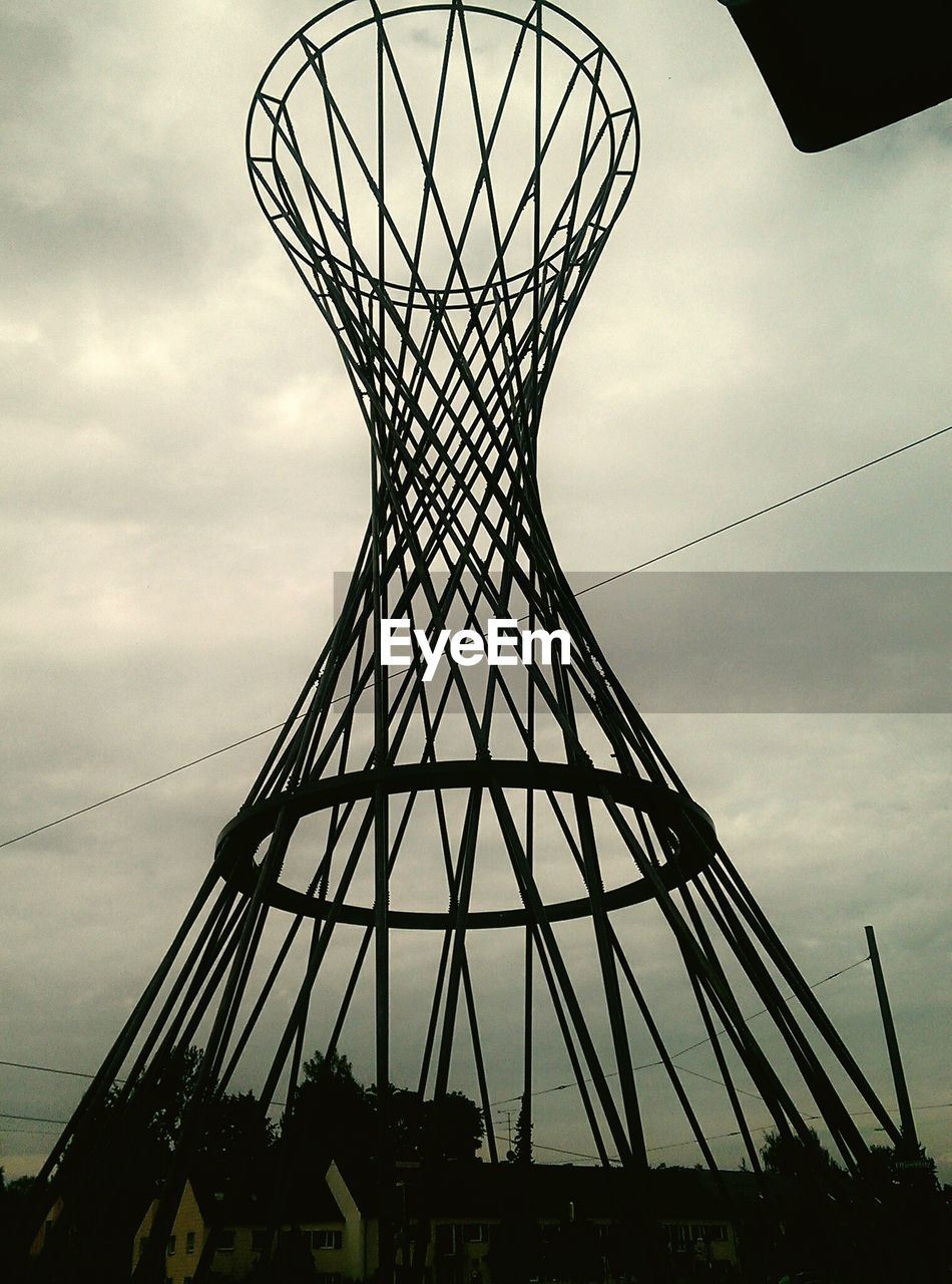 Low angle view of metallic built structure against cloudy sky