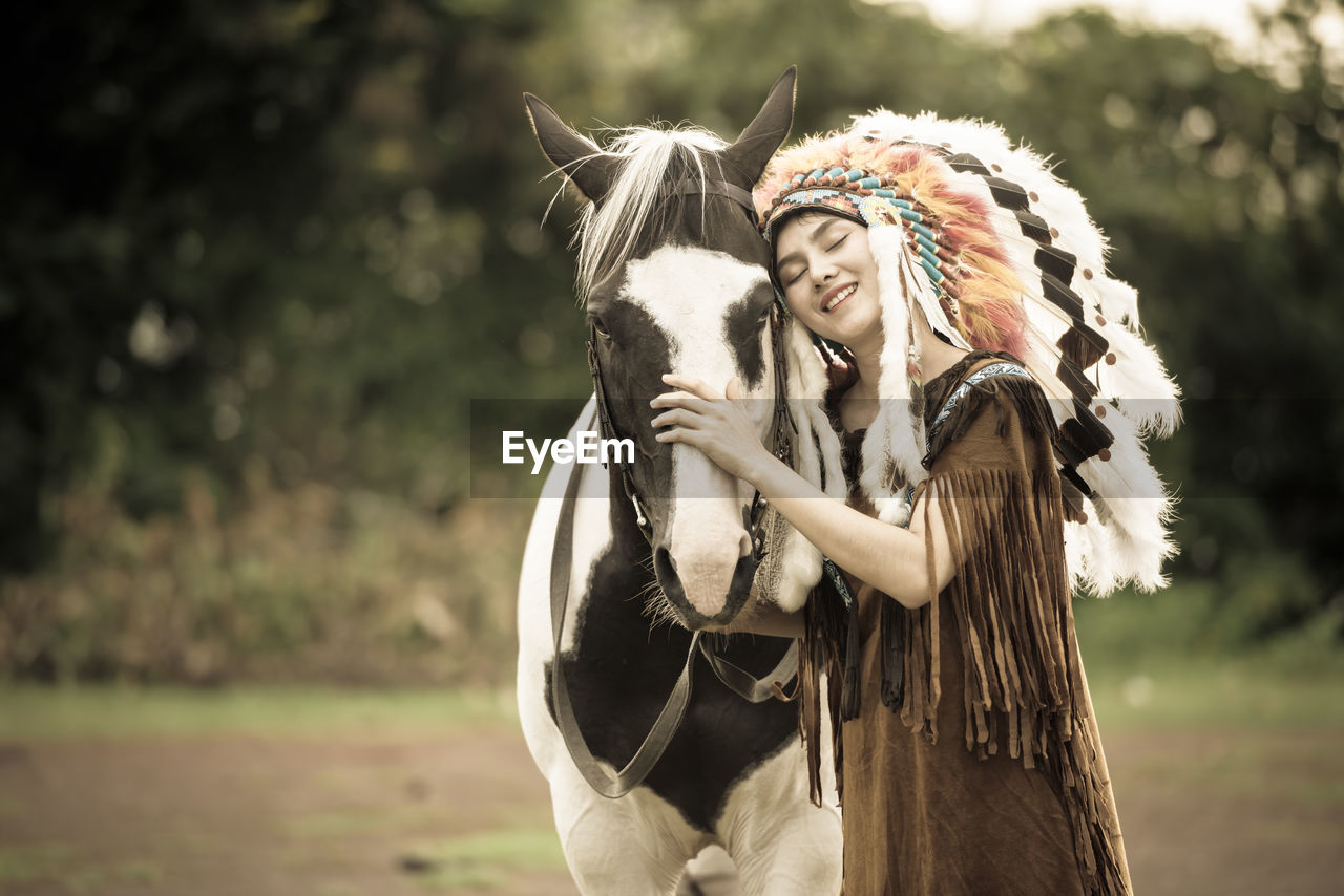 Woman stroking horse while standing on field