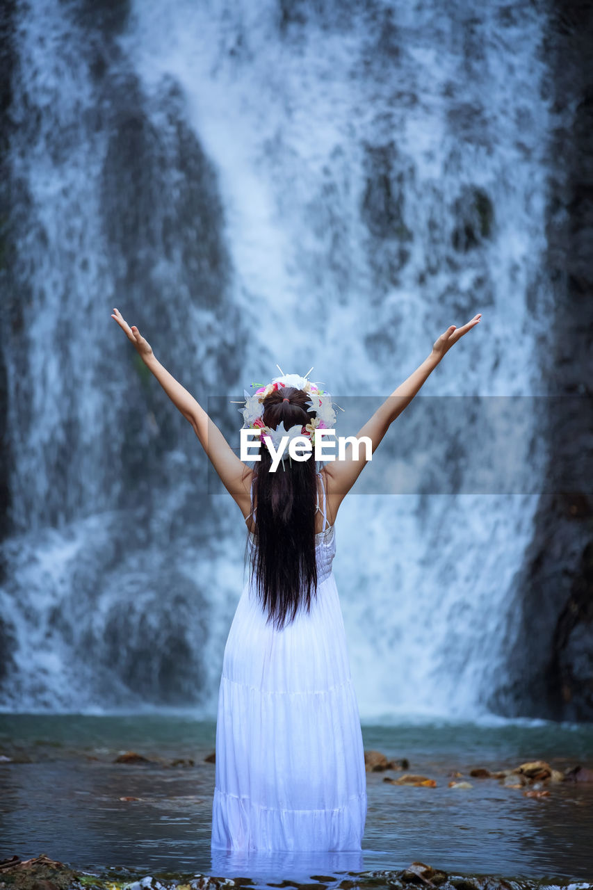 Rear view of woman standing against waterfall