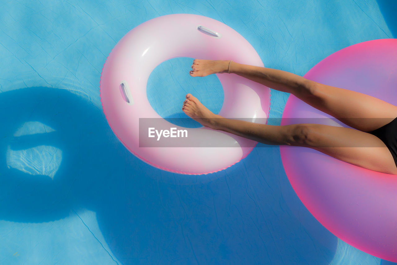 Lows section of woman relaxing on inflatable ring in swimming pool