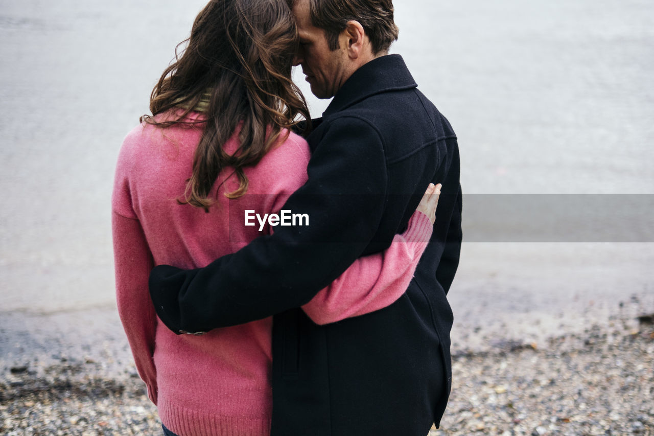 Couple embracing each other at thames riverbank, london, england