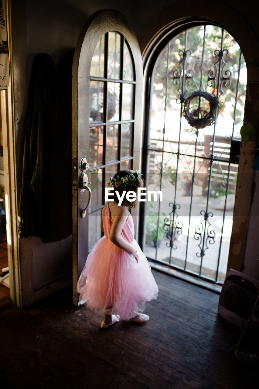 Young girl standing by front door wearing tutu and flower crown