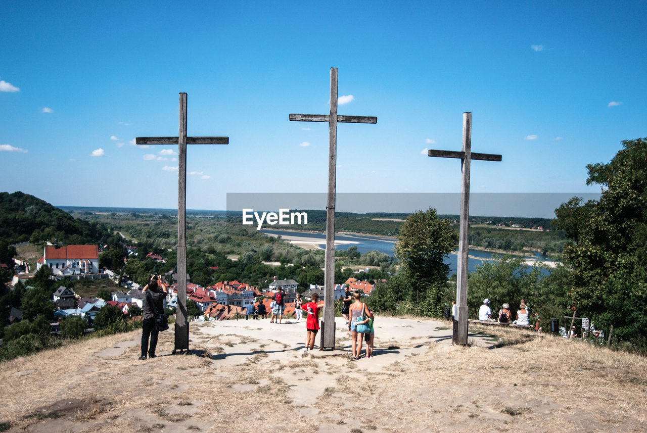 People standing by crosses against blue sky at wlodawa