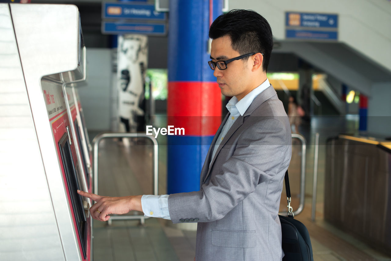 Side view of businessman using kiosk at station