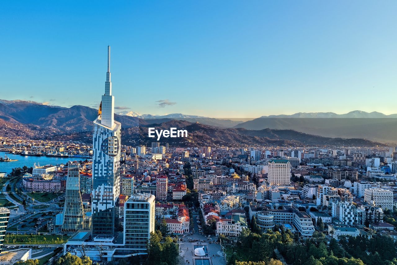 HIGH ANGLE VIEW OF CITY BUILDINGS AGAINST CLEAR SKY