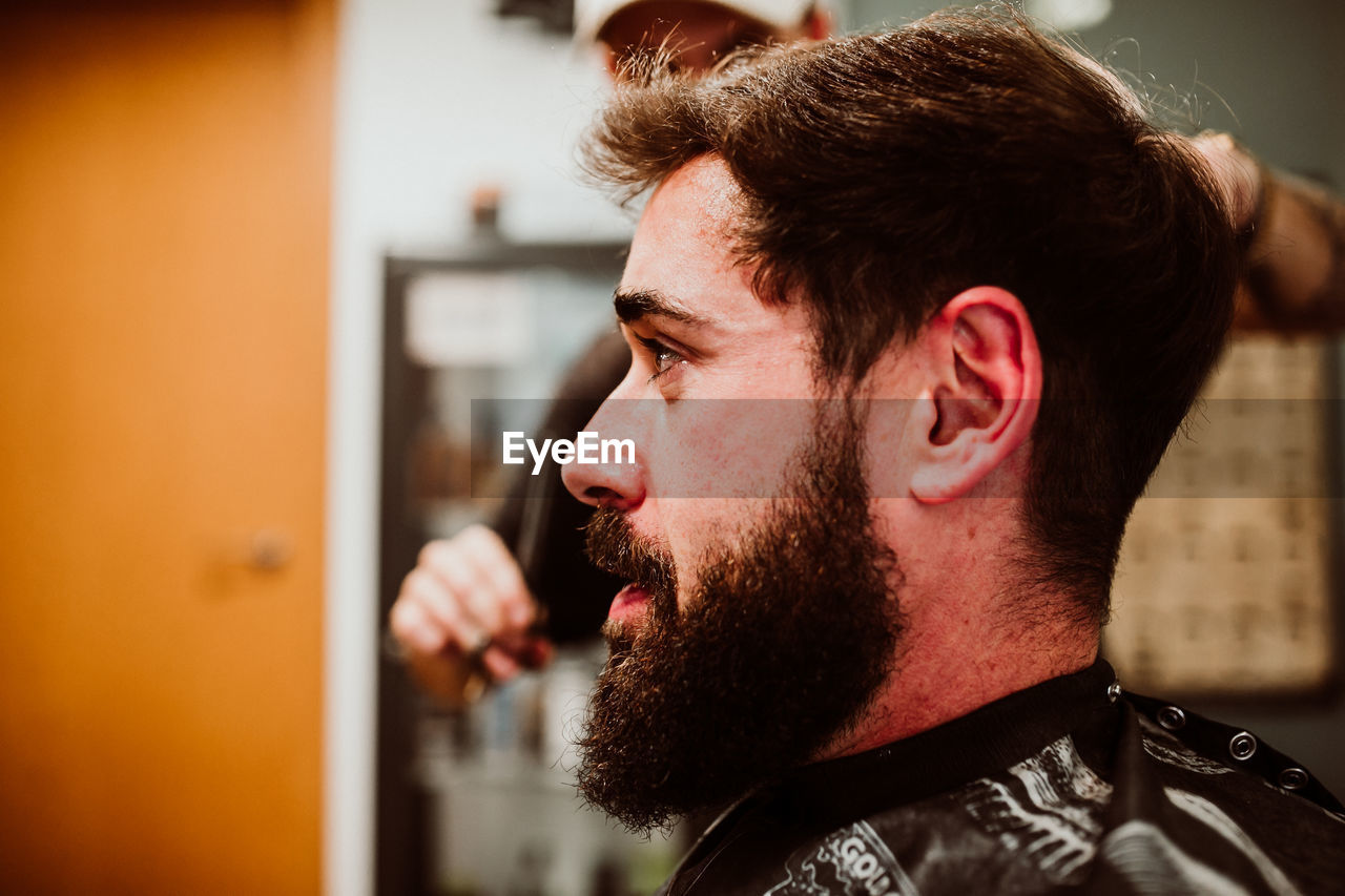 Cropped hands of barber grooming customer in salon