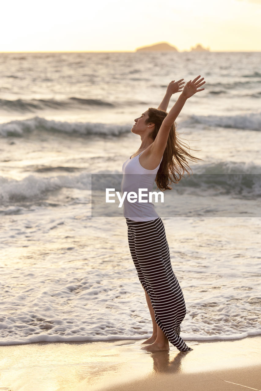 YOUNG WOMAN STANDING ON BEACH