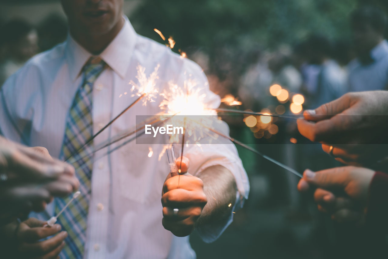 Close-up of friends igniting sparklers at party