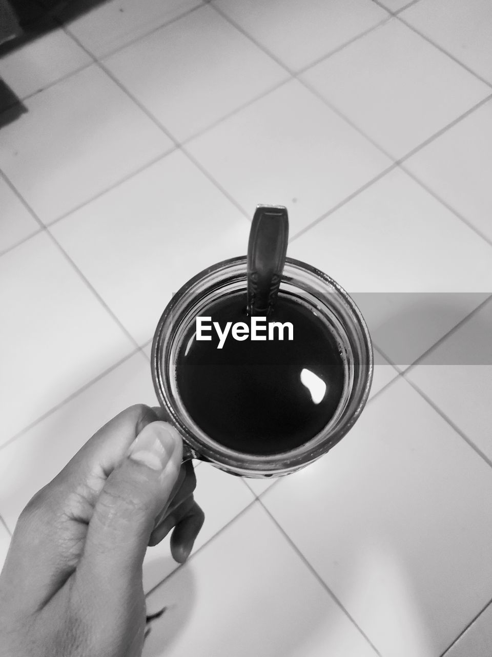 hand, black, one person, holding, indoors, black and white, circle, tile, flooring, white, personal perspective, monochrome, tiled floor, high angle view, lifestyles, monochrome photography, adult, food and drink, cup, drink, household equipment, tableware, mug, close-up, refreshment