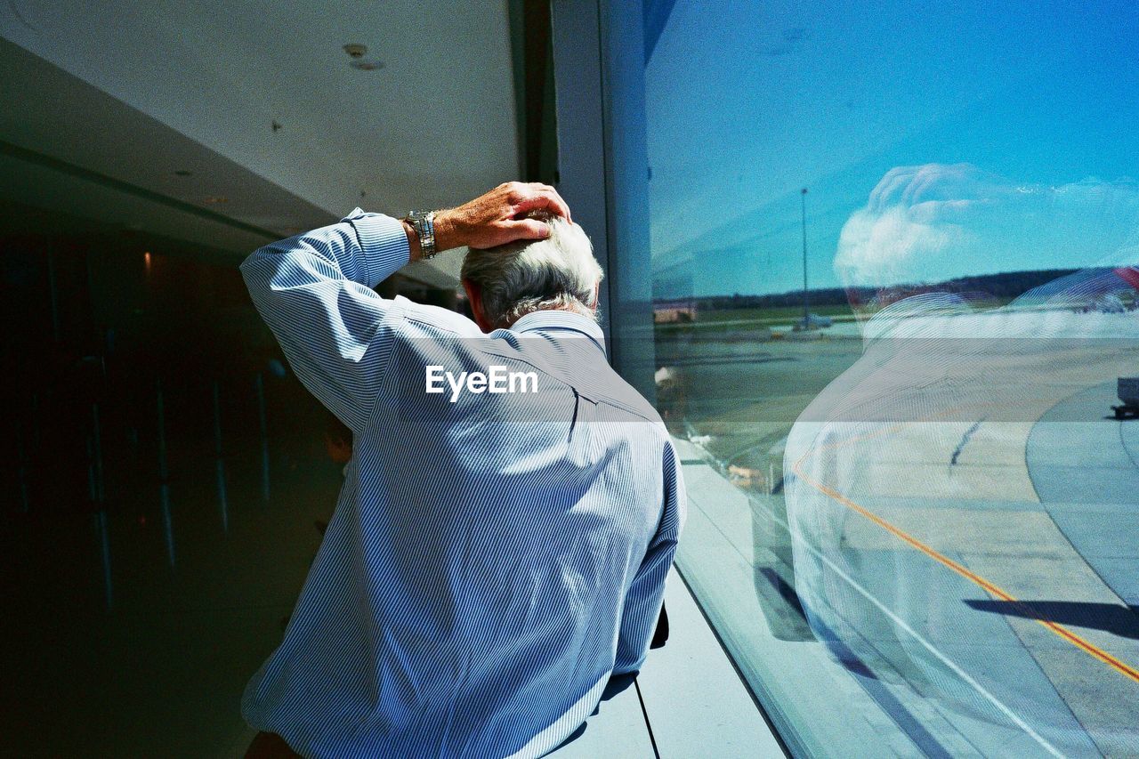 REAR VIEW OF MAN STANDING BY WINDOW AT BUS