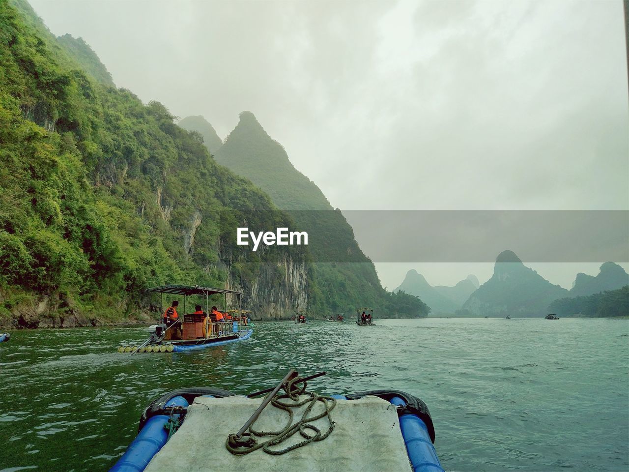 People on boats in sea against mountains