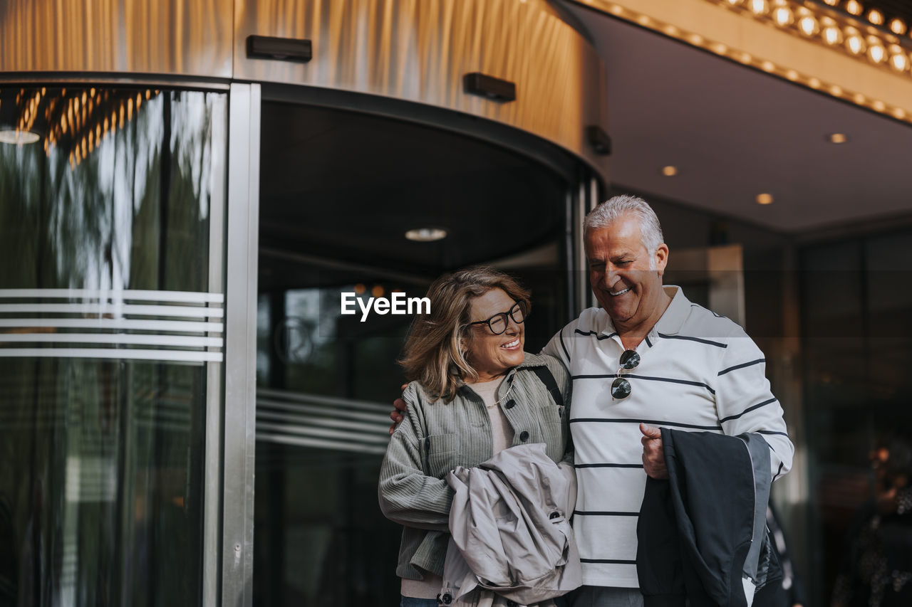 Happy male and female senior friends leaving from movie theater