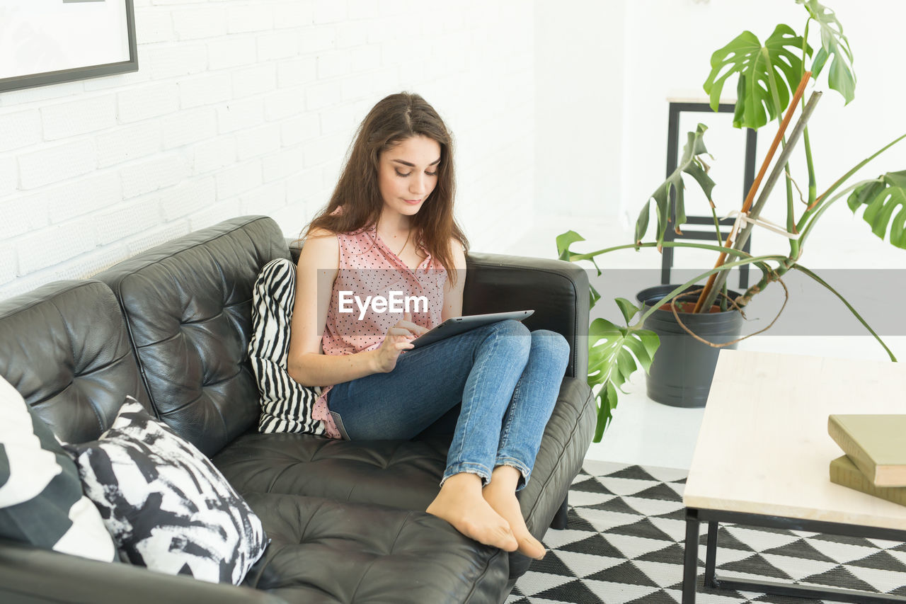 WOMAN SITTING ON SOFA AT HOME