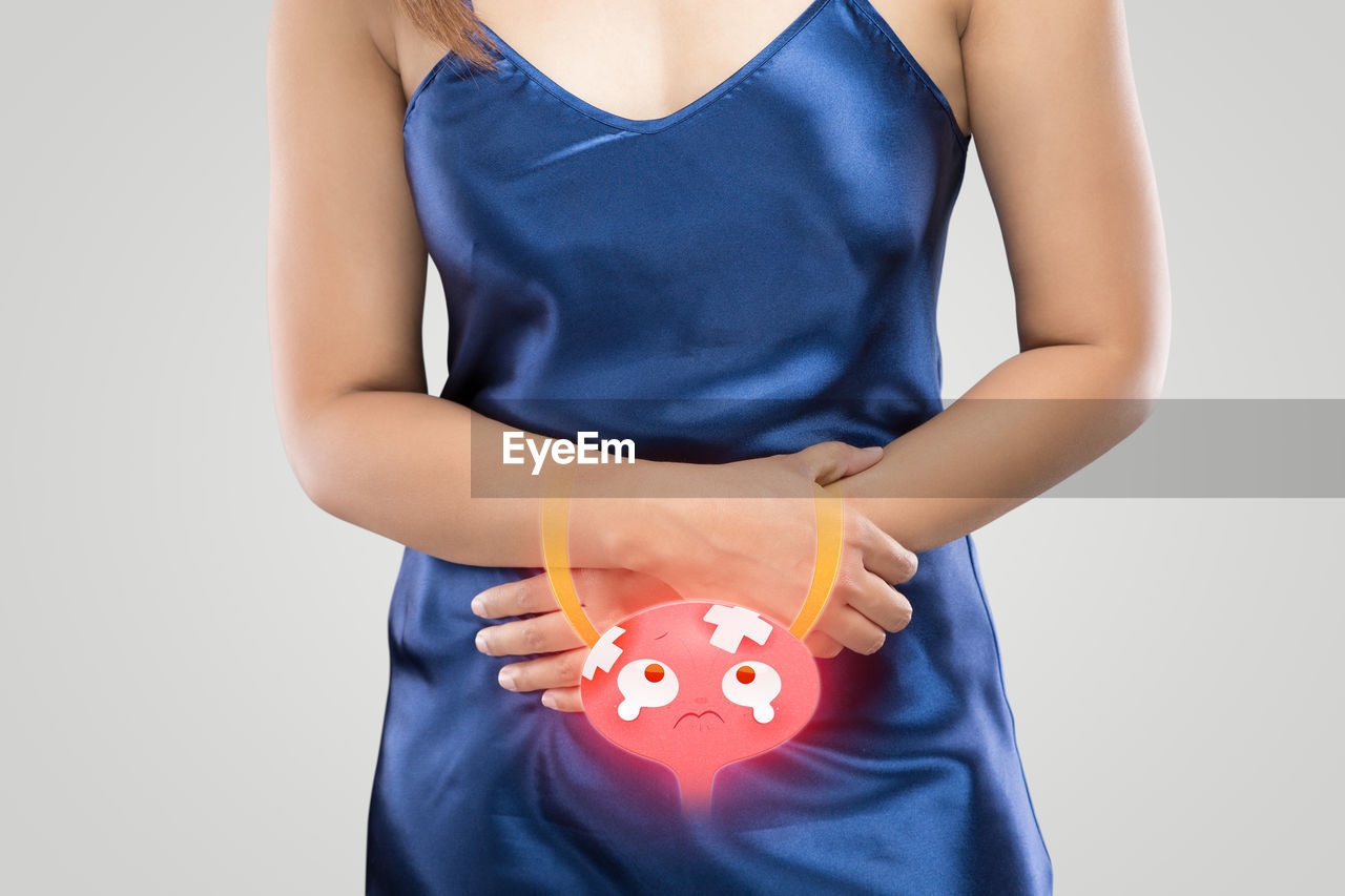 MIDSECTION OF WOMAN HOLDING CAMERA AGAINST BLUE BACKGROUND