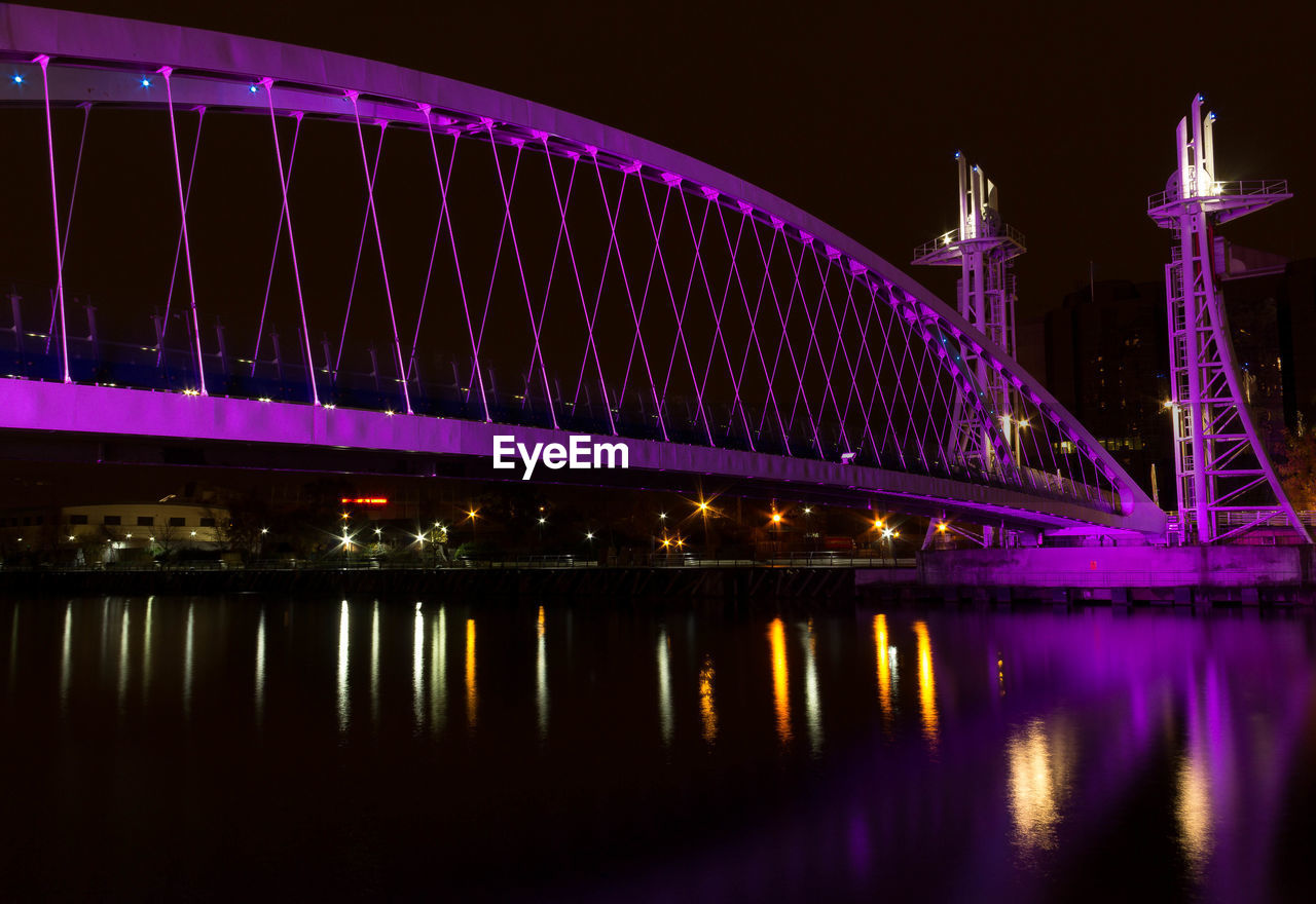 Low angle view of illuminated bridge over river at night