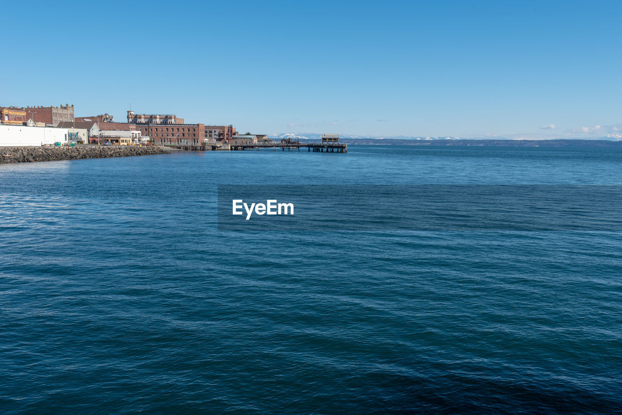 SCENIC VIEW OF SEA AND BUILDINGS AGAINST CLEAR SKY