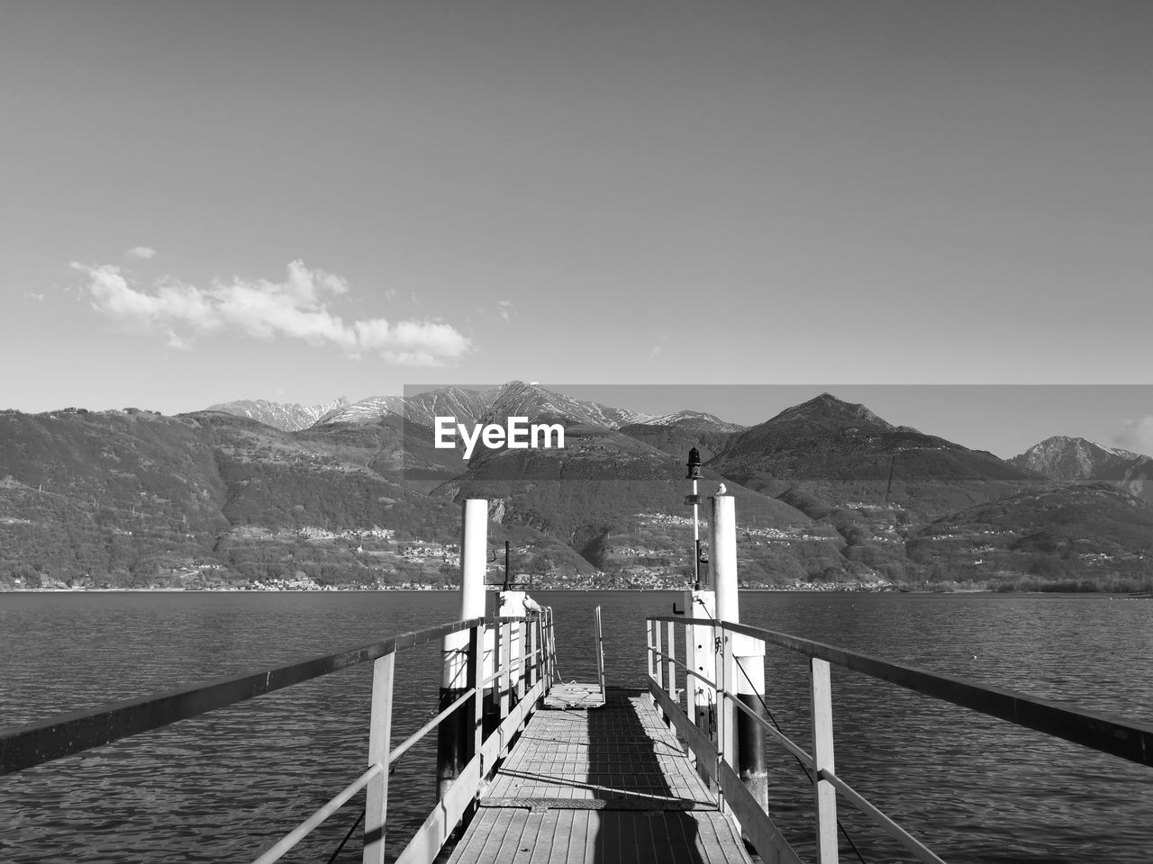 Pier leading towards mountains against sky