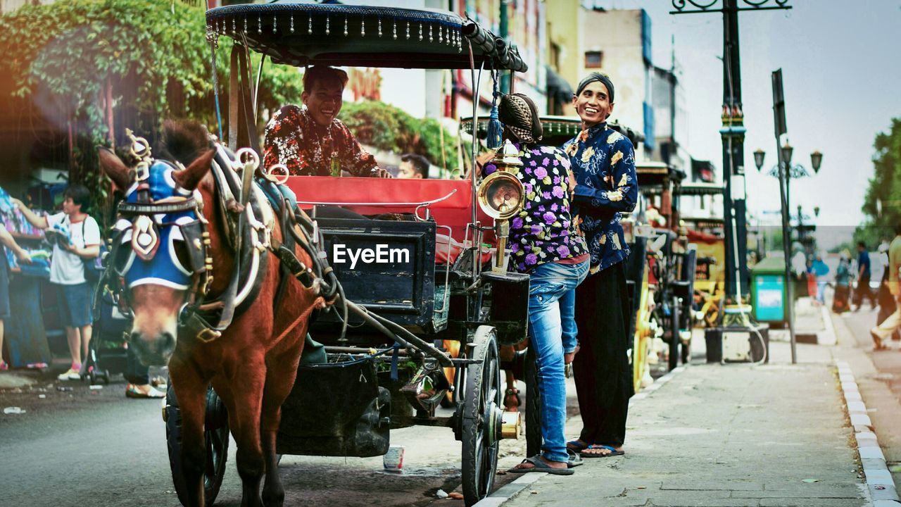 Happy friends with horse cart on road in city