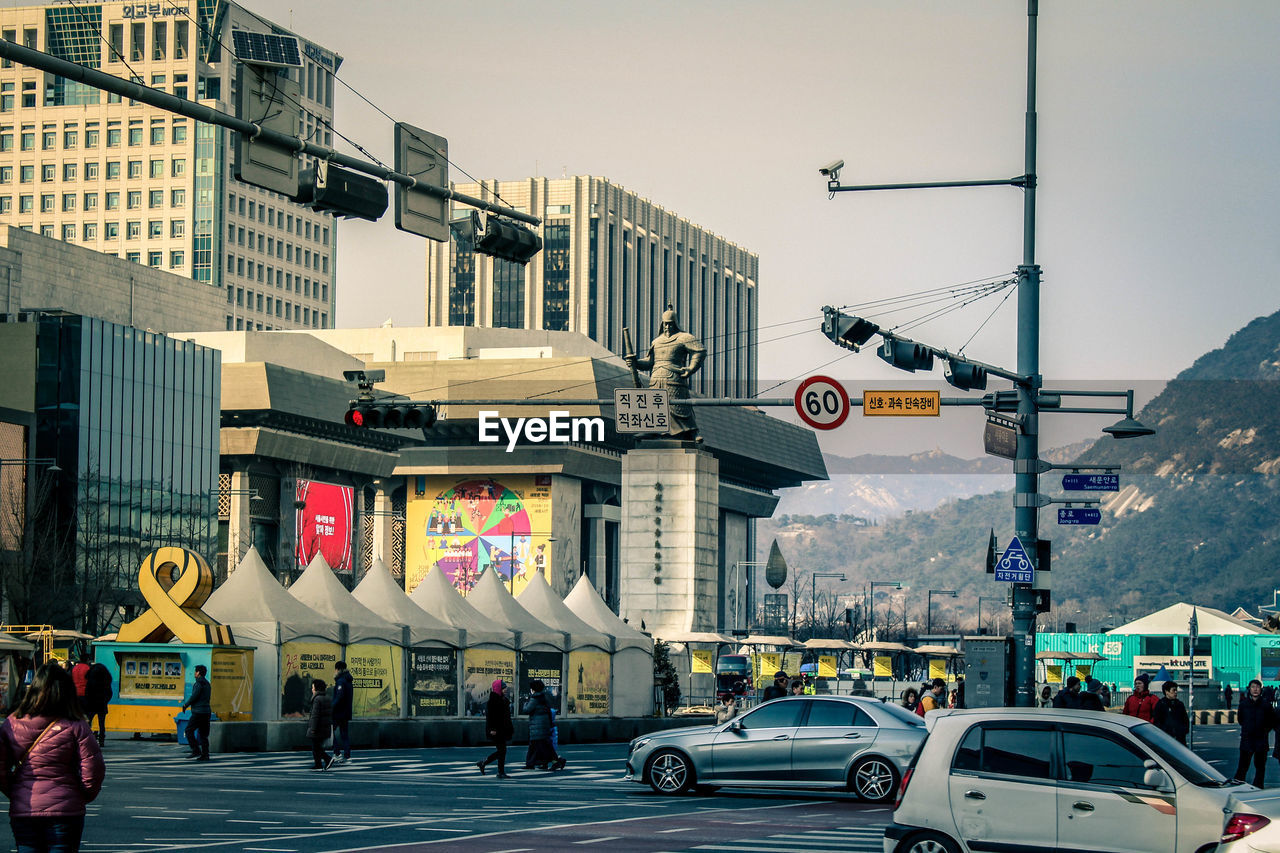 CARS ON ROAD BY BUILDINGS IN CITY