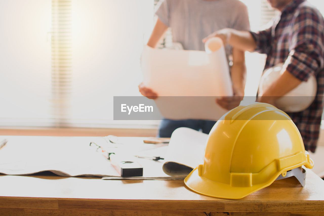 REAR VIEW OF PEOPLE WORKING ON TABLE IN OFFICE