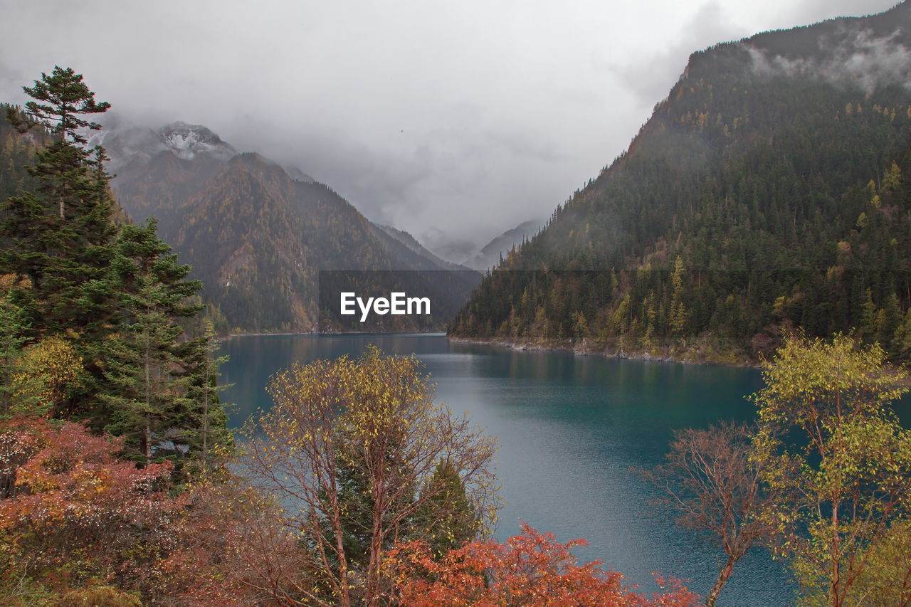 Scenic view of lake and foggy autumn mountains against sky with blue lake
