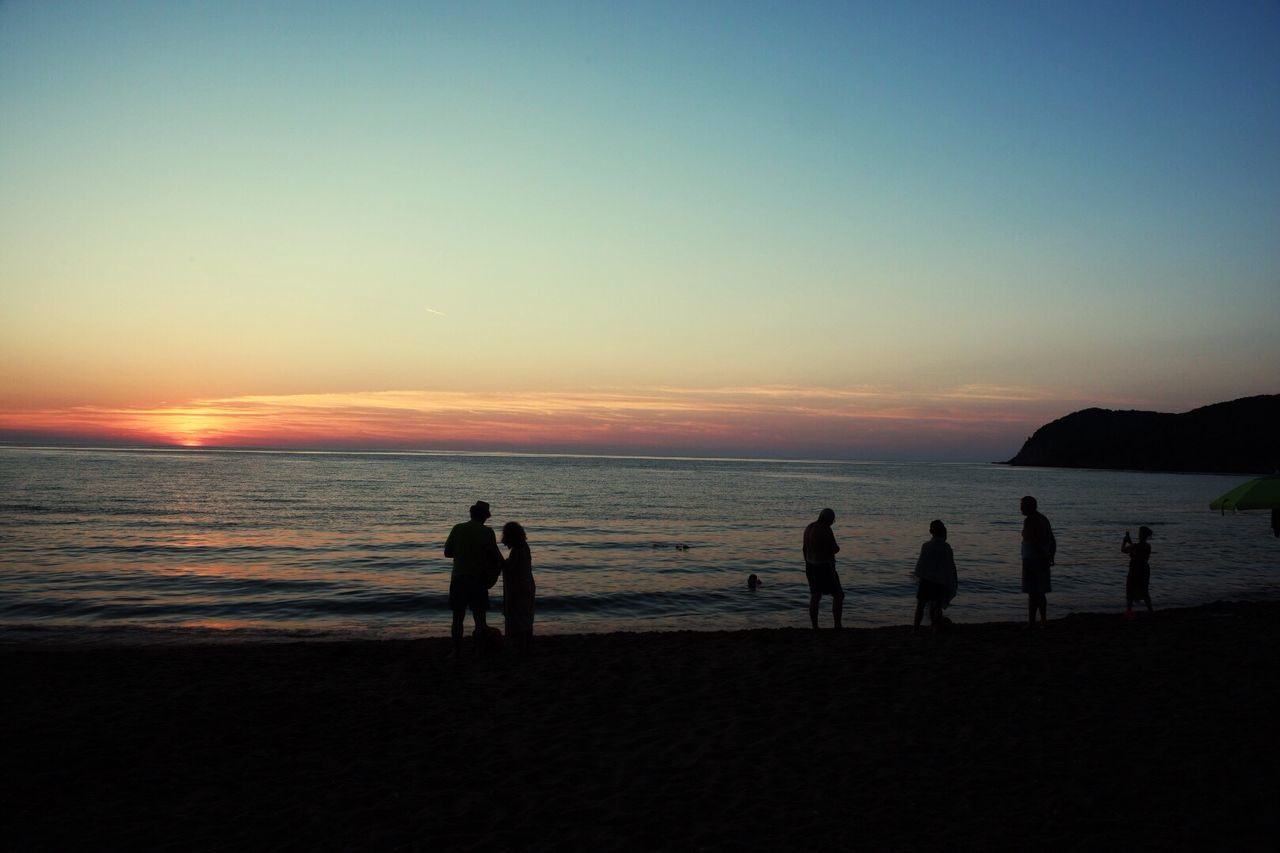 Silhouette people at beach during sunset