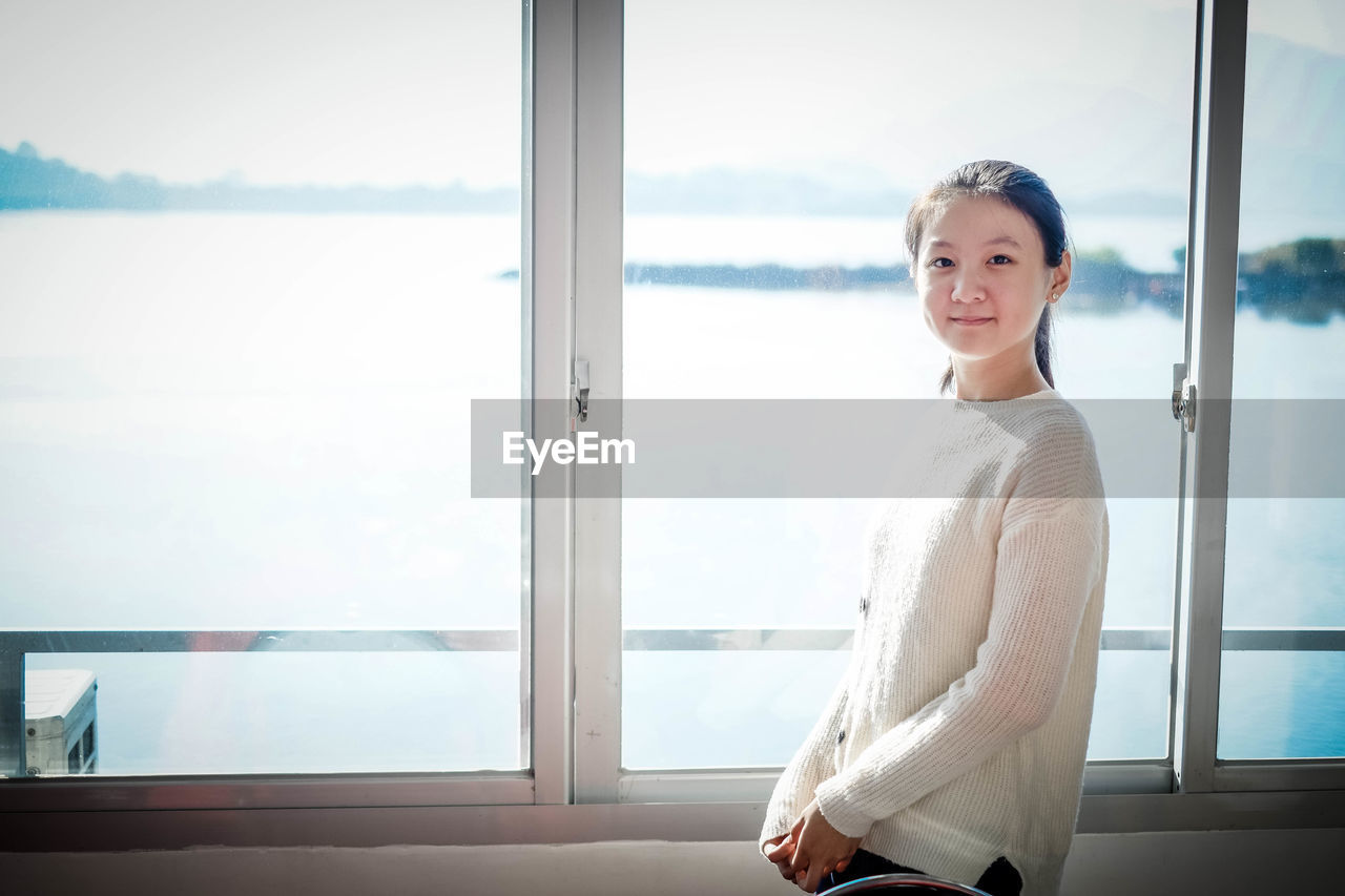 Portrait of smiling girl standing by window