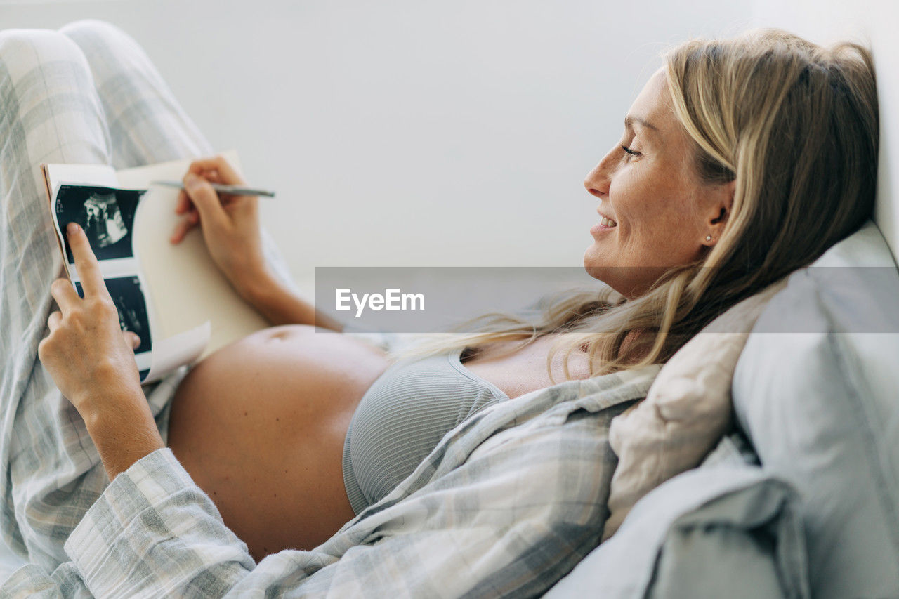 A pregnant woman makes notes in a notebook about the ultrasound result.