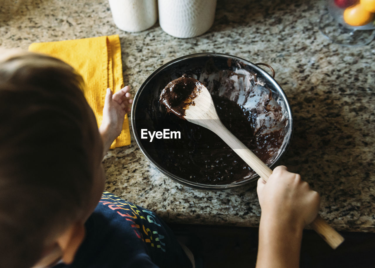 High angle view of boy making chocolate sauce in kitchen