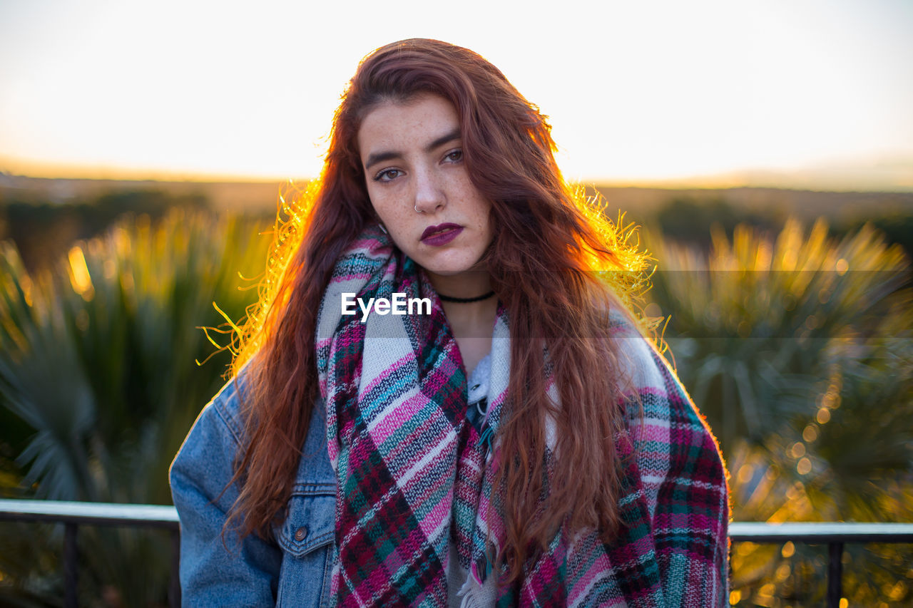 Portrait of beautiful young woman standing against clear sky