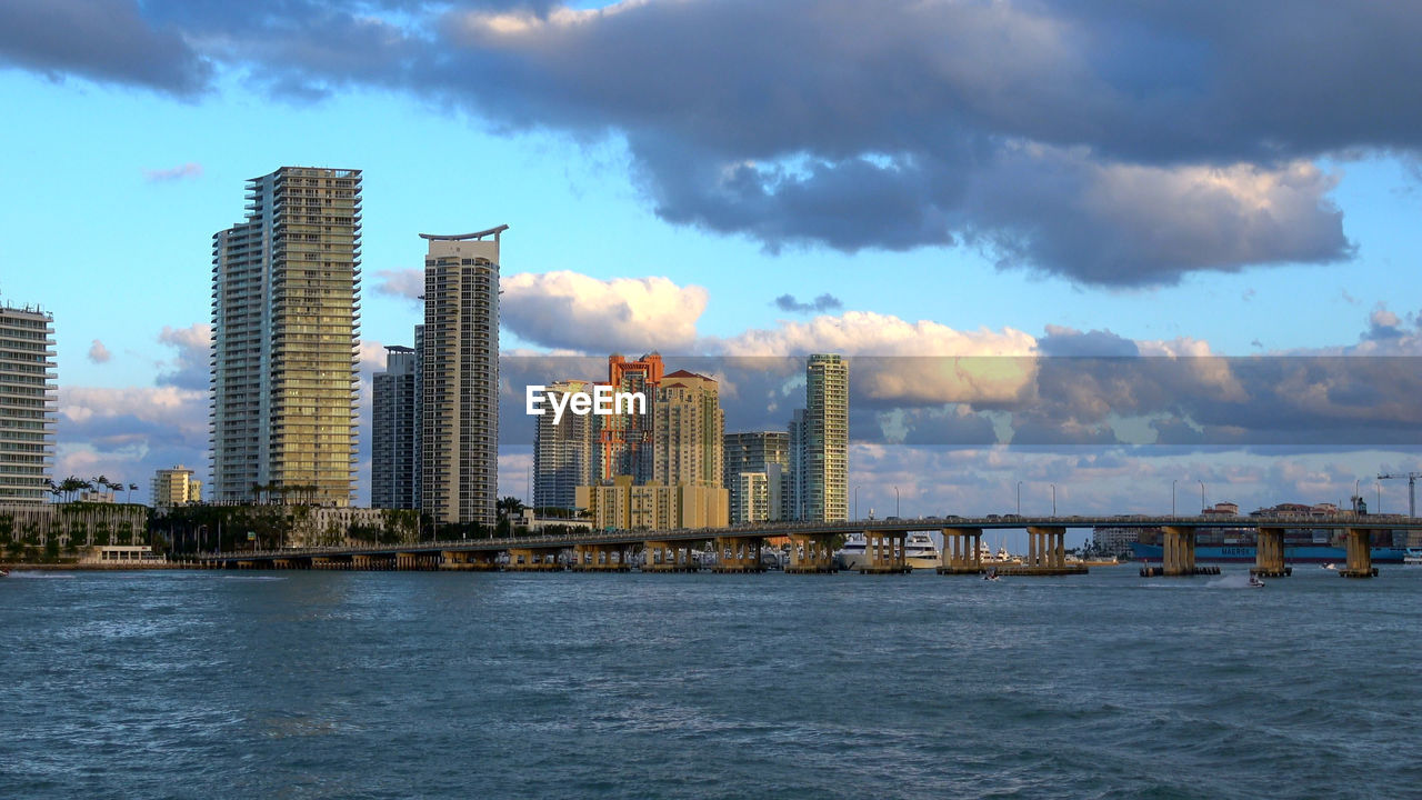 SCENIC VIEW OF SEA BY MODERN BUILDINGS AGAINST SKY