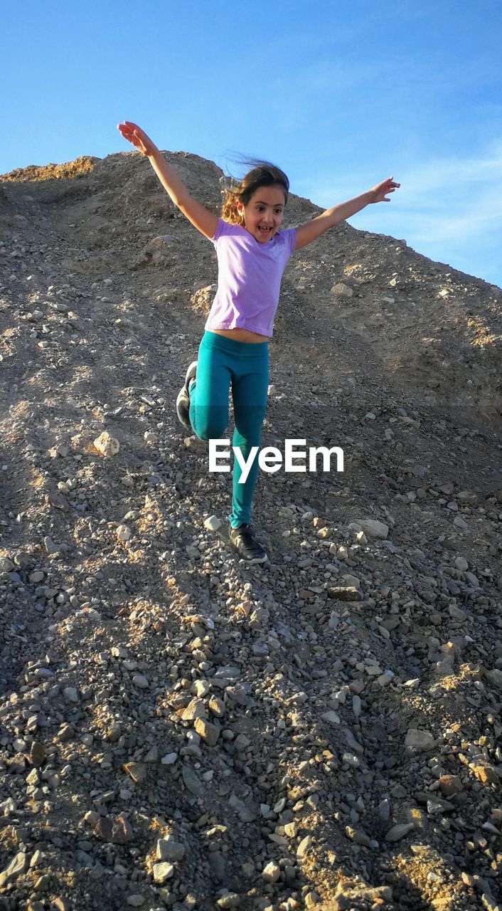 FULL LENGTH OF GIRL WITH ARMS RAISED ON LAND