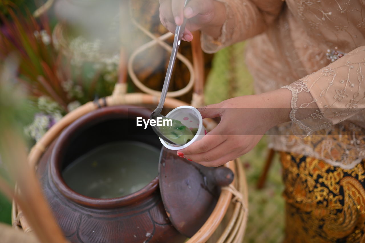 Close-up of hand pouring tea cup